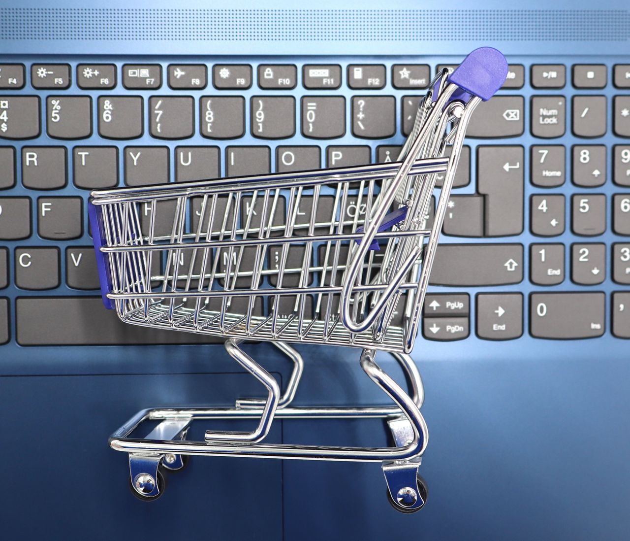 mobile-02 A miniature shopping cart sitting on a laptop keyboard, representing online shopping and e-commerce.